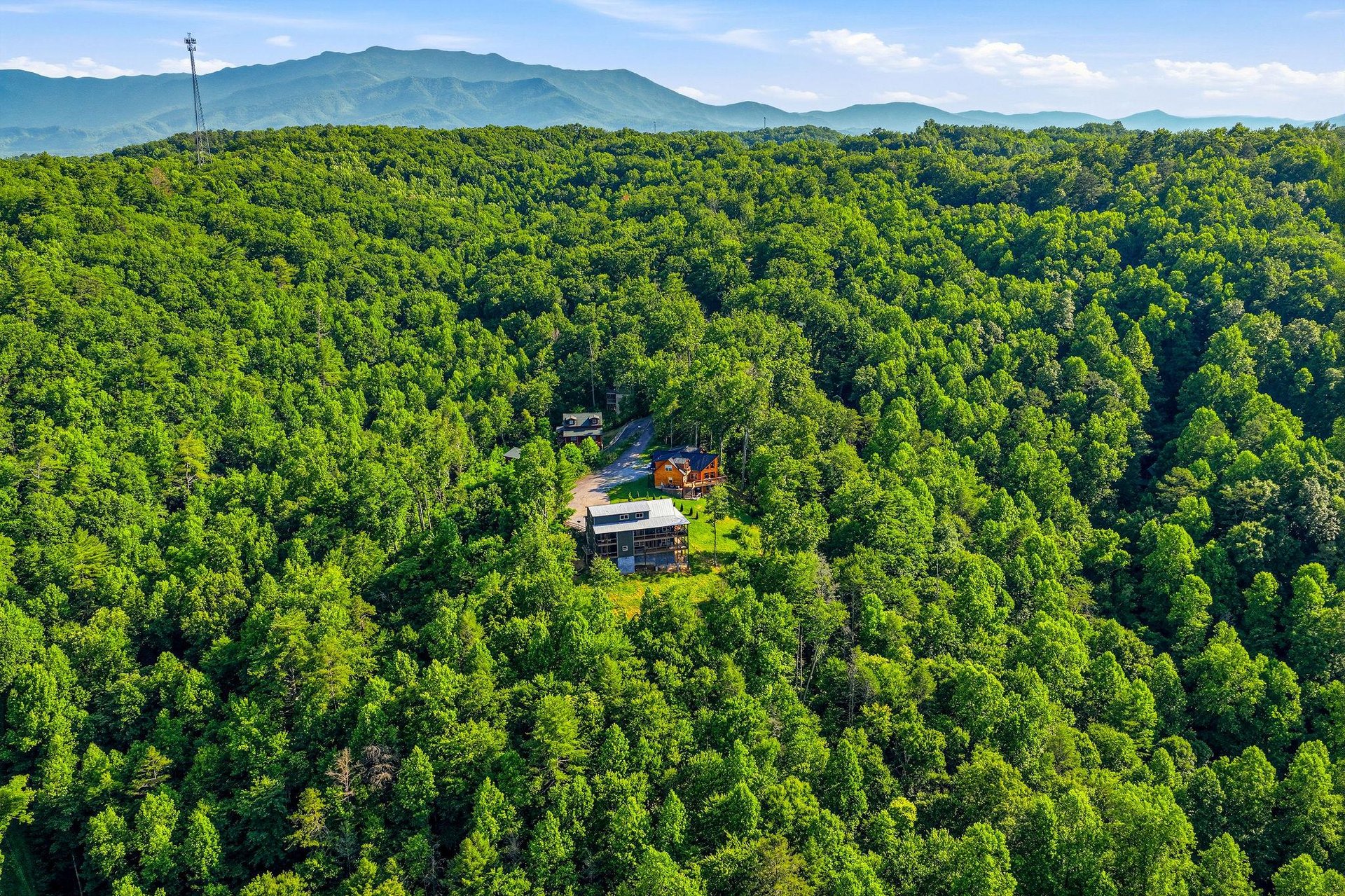 A secluded mountain retreat nestled in lush forest with dramatic peaks rising in the distance.