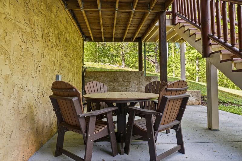 Unwind on your covered patio with comfortable seating for outdoor meals and relaxation, surrounded by natural greenery and stone details.