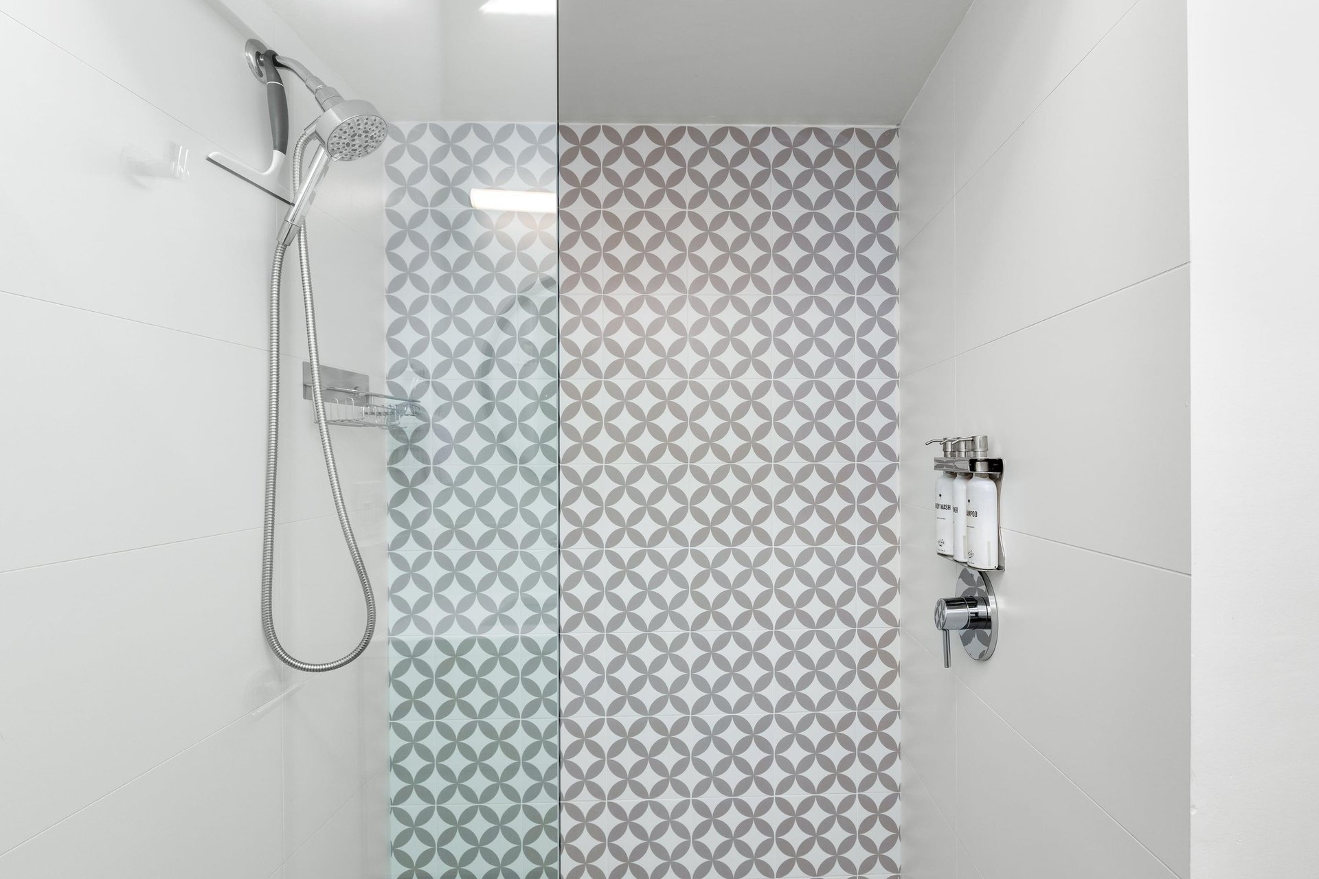 Step into your private spalike shower featuring elegant geometric tiles and a luxurious rainfall showerhead for the perfect start to your morning.
