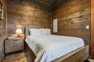 Unwind in your cozy cabinstyle bedroom, where warm wood walls create a peaceful retreat. Sink into crisp linens and feel the mountain charm surround you.