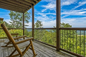 A covered deck perched high above lush treetops offers sweeping views of rolling hills and distant horizons—perfect for sipping morning coffee or watching the sunset from your private retreat.