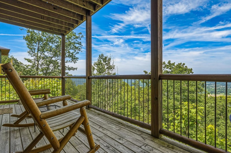 A covered deck perched high above lush treetops offers sweeping views of rolling hills and distant horizons—perfect for sipping morning coffee or watching the sunset from your private retreat.
