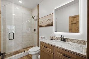 Unwind in your spalike bathroom featuring granite counters, modern shower, and mountain artwork that brings nature indoors.