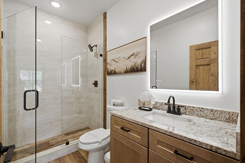 Unwind in your spalike bathroom featuring granite counters, modern shower, and mountain artwork that brings nature indoors.