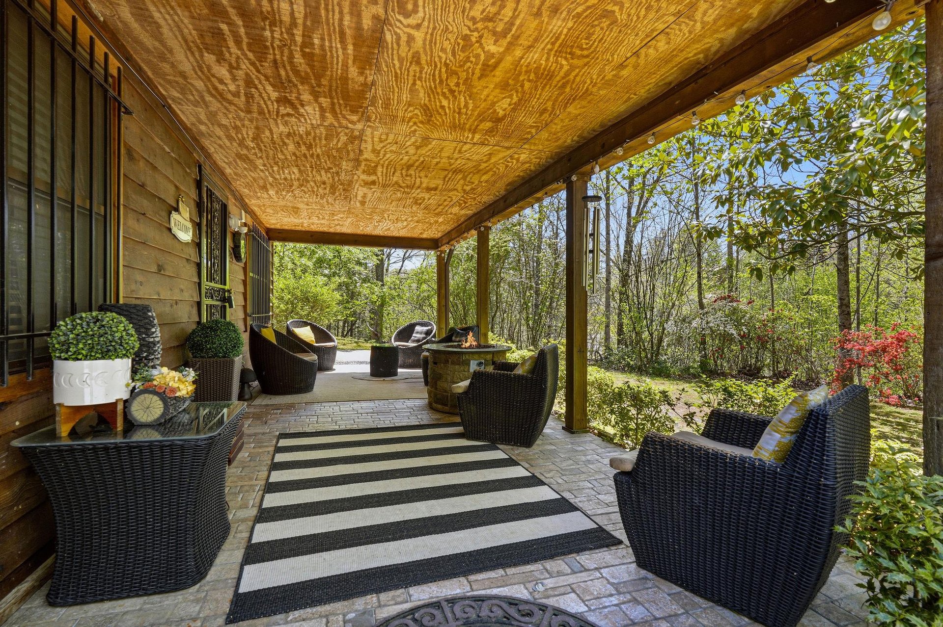 Unwind in your private covered patio, where comfortable wicker seating invites you to relax surrounded by lush garden views.