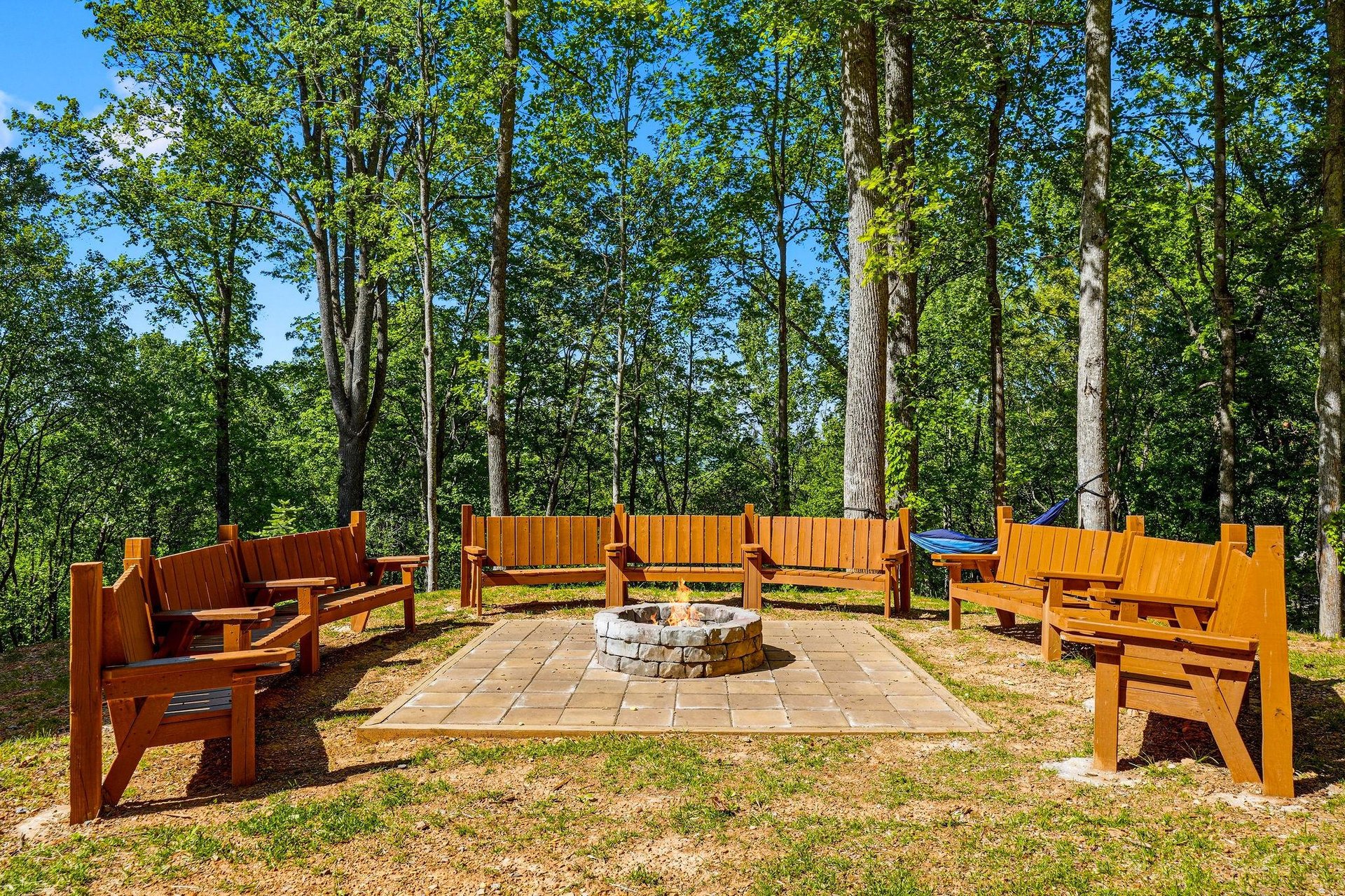 Gather around the fire pit with friends, surrounded by handcrafted wooden benches in this peaceful forest clearing.