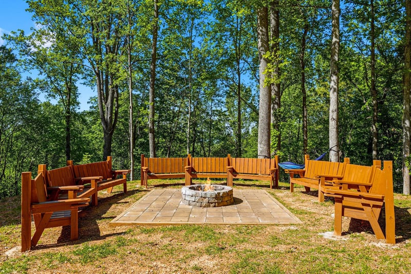 Gather around the fire pit with friends, surrounded by handcrafted wooden benches in this peaceful forest clearing.