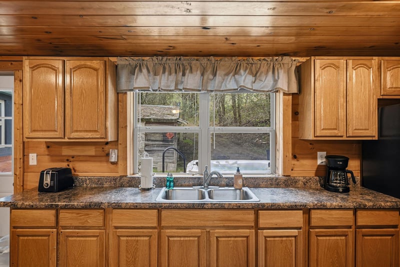 Cook your favorite meals in this warm rustic kitchen with granite counters, rich wood cabinets, and peaceful garden views.