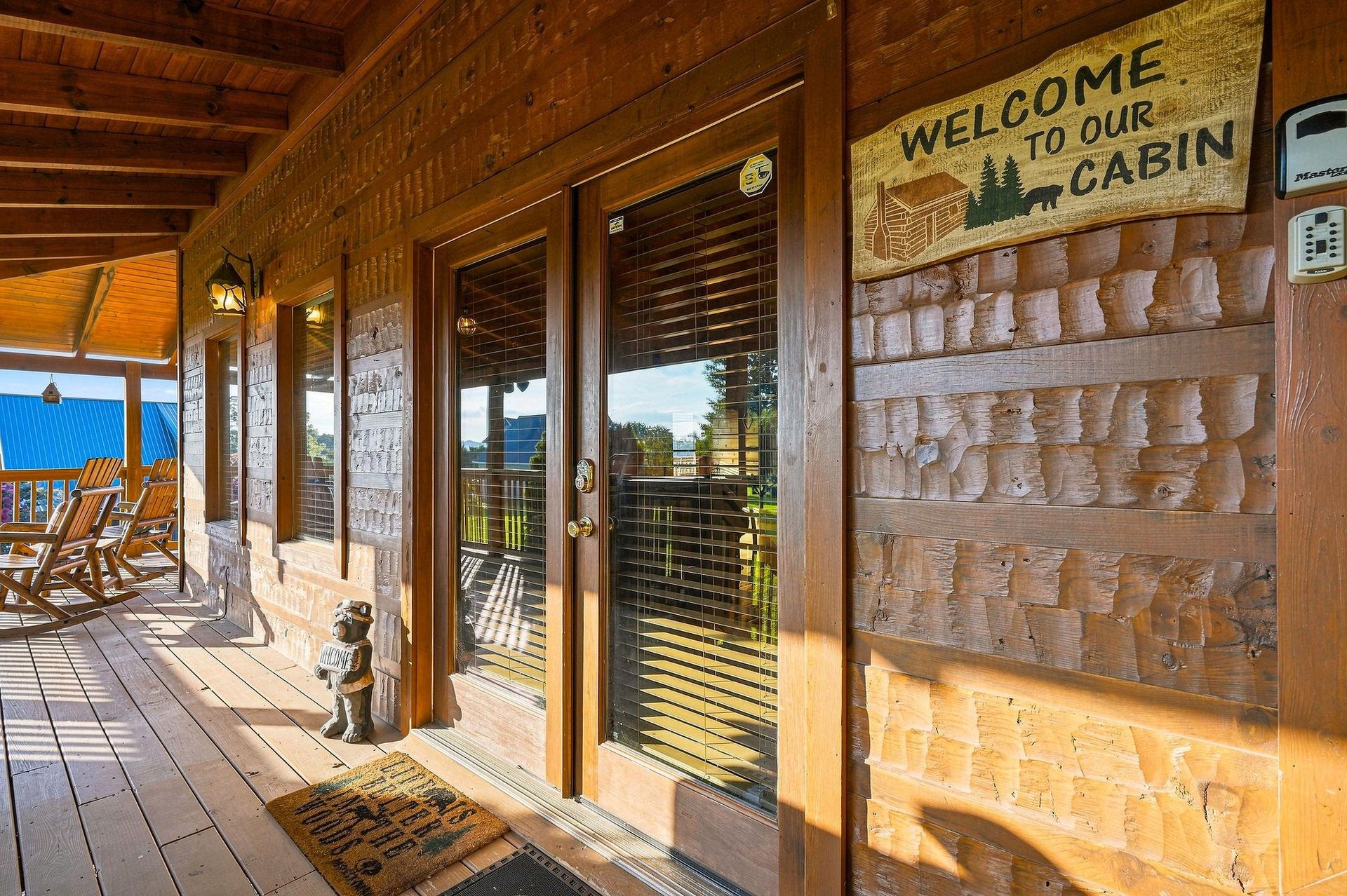Step onto your private covered porch where rocking chairs and rustic mountain charm await. The welcoming cabin entrance sets the tone for a cozy, unforgettable retreat.