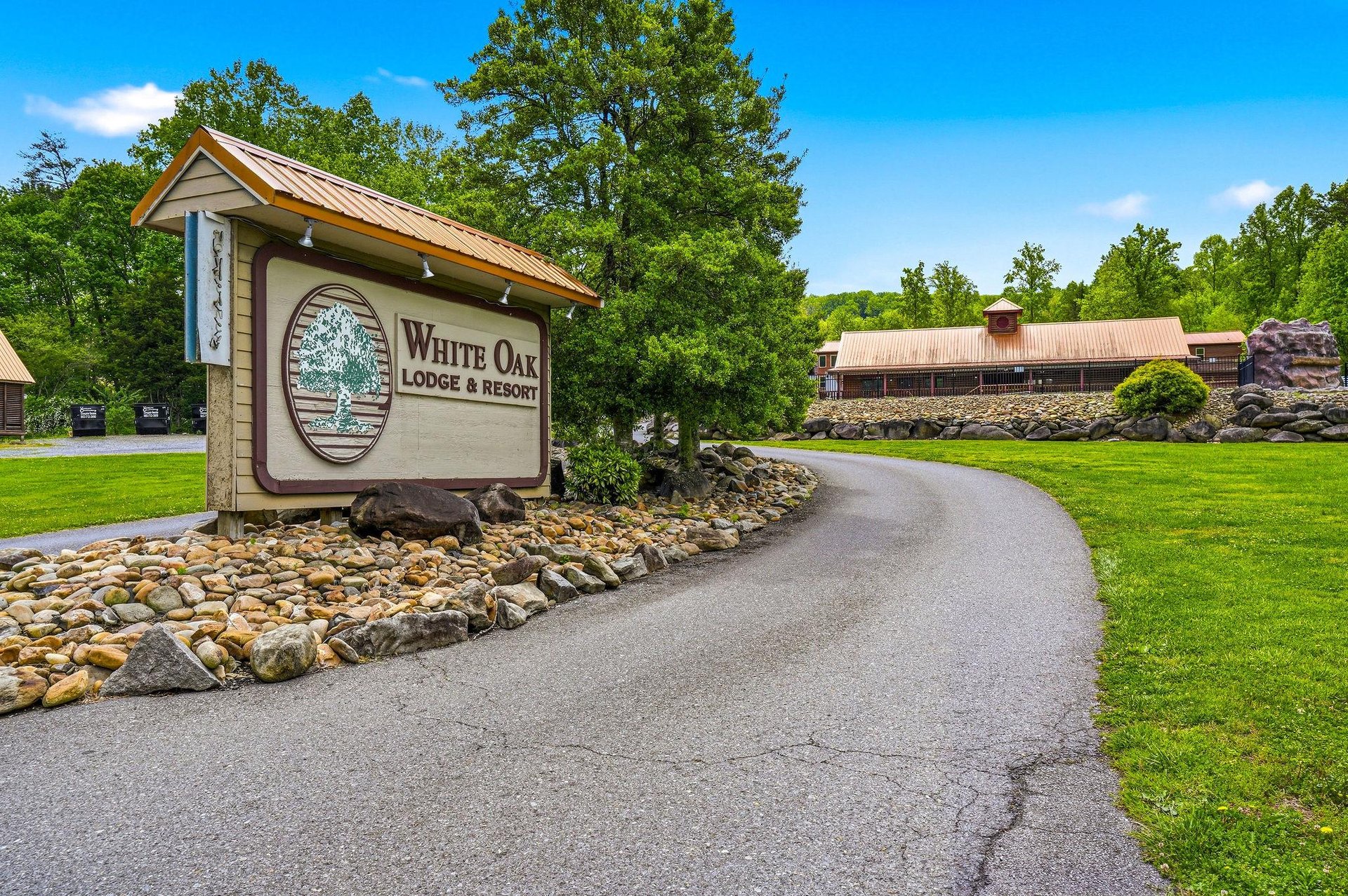 White Oak Lodge  Resort entrance sign welcomes guests with rustic charm amid lush green lawns and mature trees.