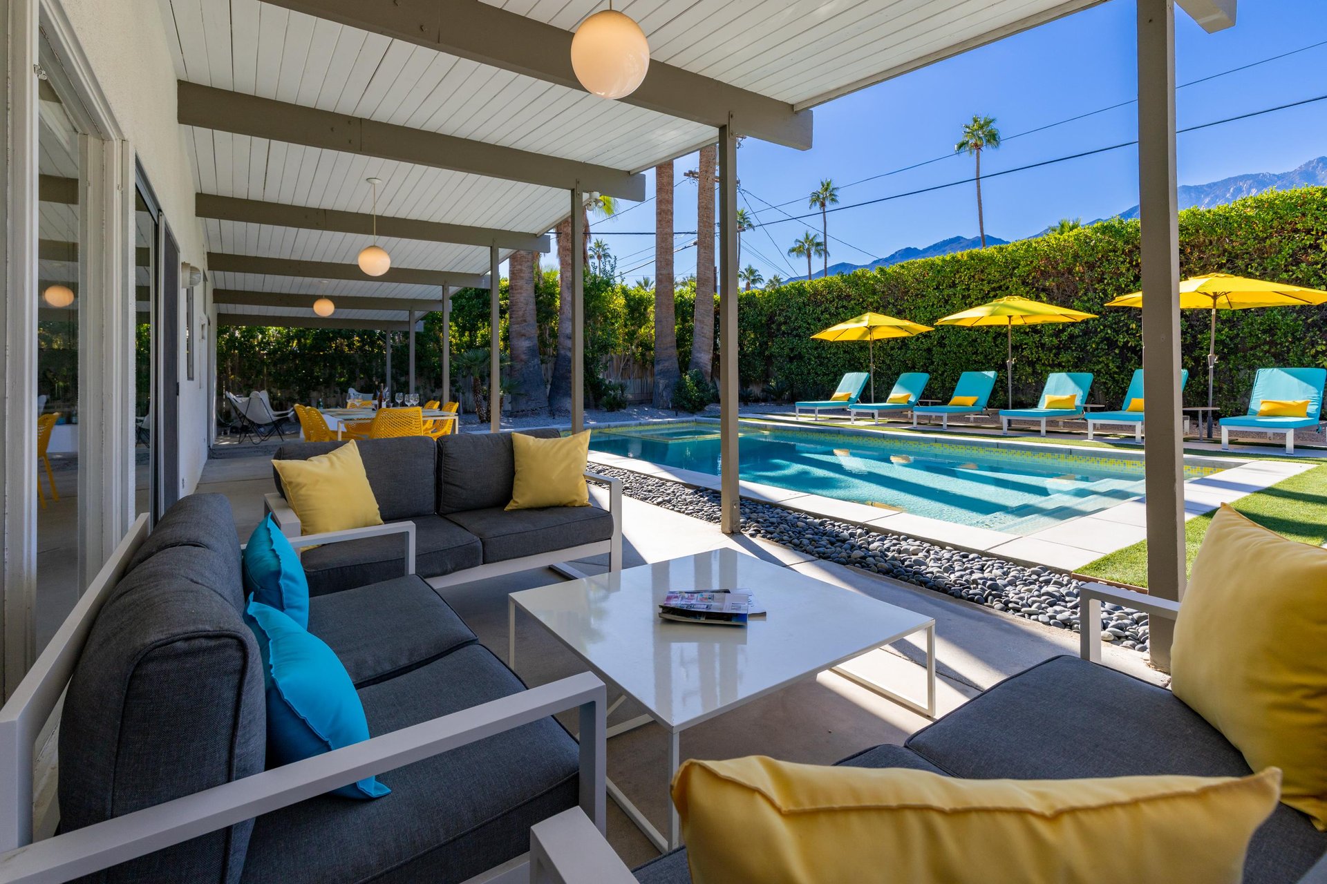 Sink into plush seating on your covered patio, where stylish comfort meets poolside luxury under desert mountain views.