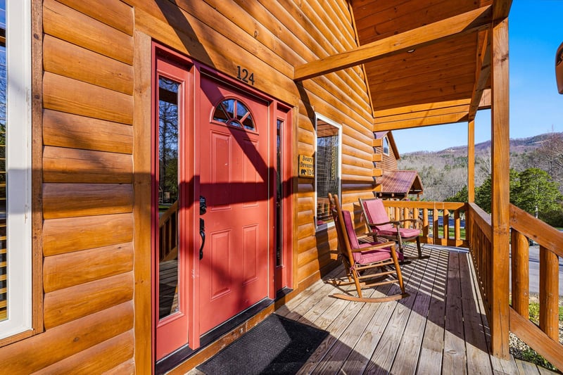 Charming log cabin entrance with rustic porch and mountain views welcomes guests to a peaceful retreat.