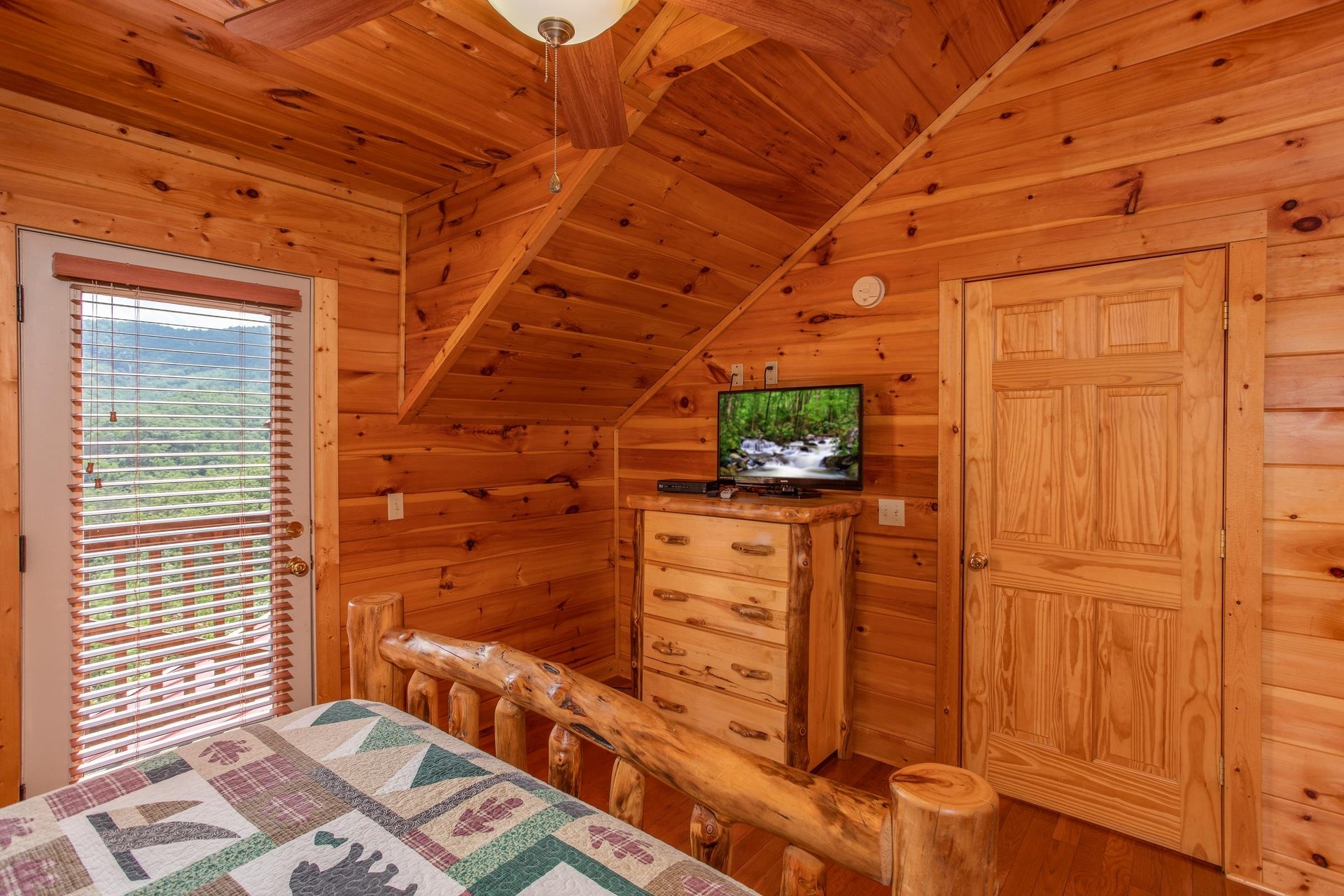 Queen bedroom with deck access, a dresser, and TV at Four Seasons Lodge, a 3bedroom cabin rental located in Pigeon Forge