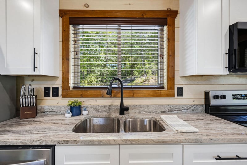 Your fullyequipped kitchen features gleaming granite countertops, a double sink, and a charming window framed in warm wood that invites natural light and garden views.