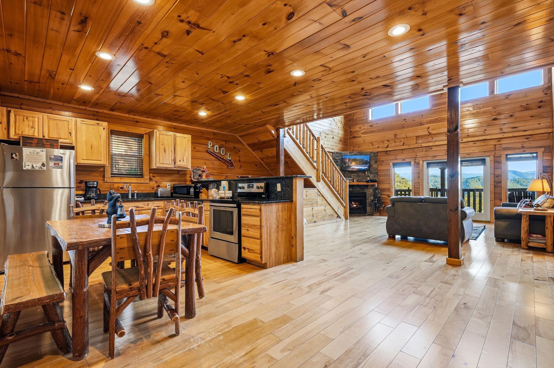 Rustic woodpaneled ceiling and walls create your cozy mountain retreat, where openconcept living flows seamlessly from modern kitchen to comfortable lounge with stunning views beyond the windows.