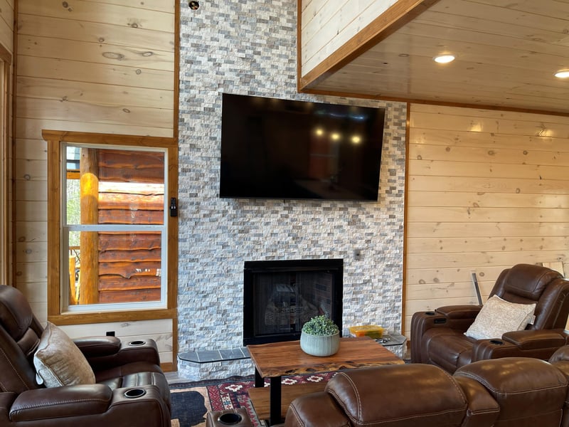 Sink into plush leather recliners by your stone fireplace, where warmth and entertainment blend seamlessly for cozy evenings.