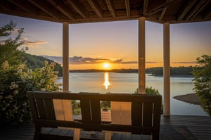 A covered deck frames a tranquil lake as the sun sets over the water and surrounding hills, creating a peaceful arrival scene for the property.