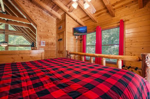 Drift off under vaulted wood ceilings and cozy plaid bedding, with soft natural light streaming in through the windows. Your rustic retreat feels warm, inviting, and perfectly private.
