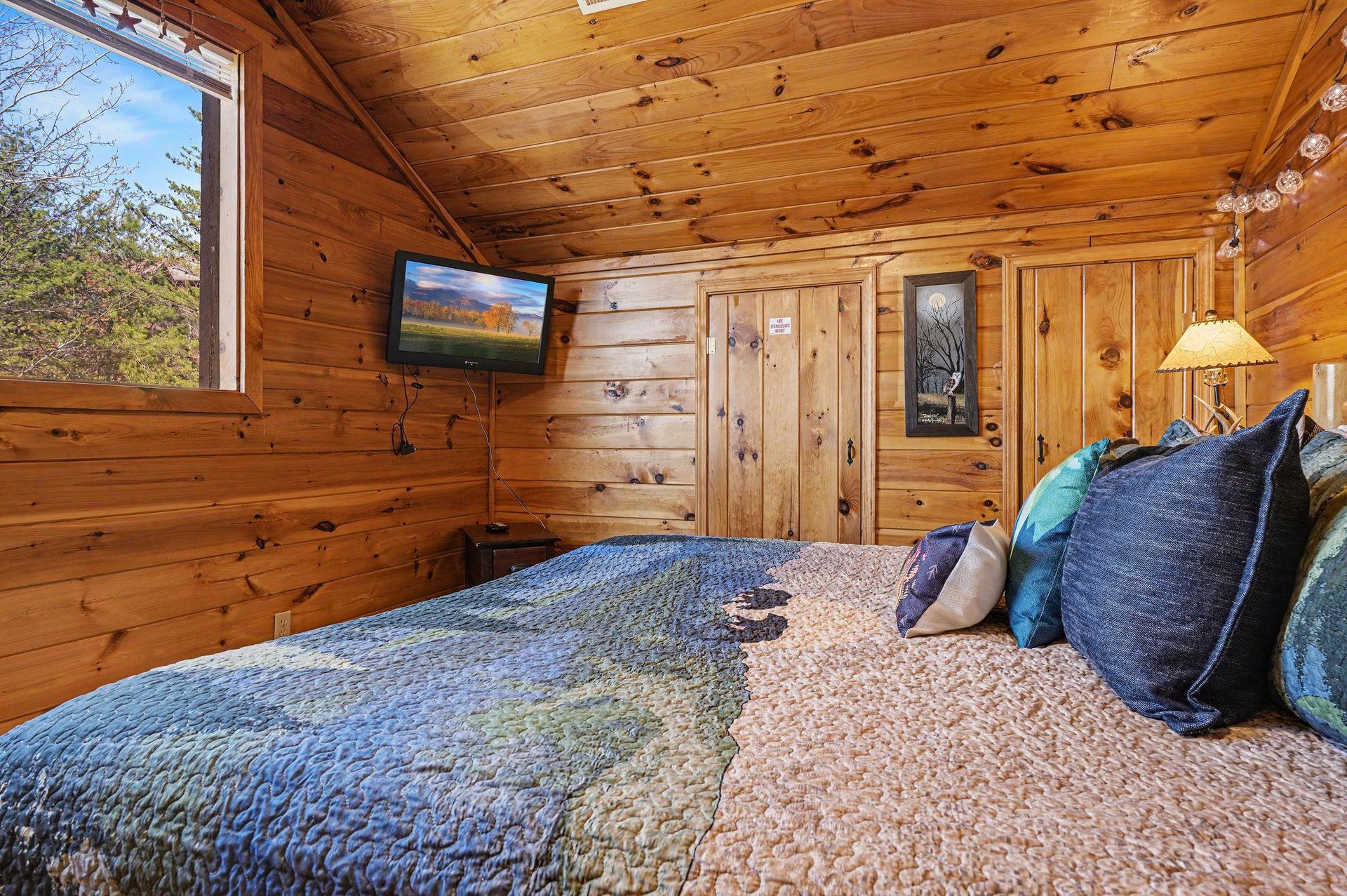 Snuggle into your cozy cabin bedroom, where warm wood surrounds you and forest views greet you each morning through large windows.