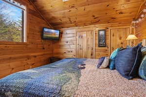 Snuggle into your cozy cabin bedroom, where warm wood surrounds you and forest views greet you each morning through large windows.
