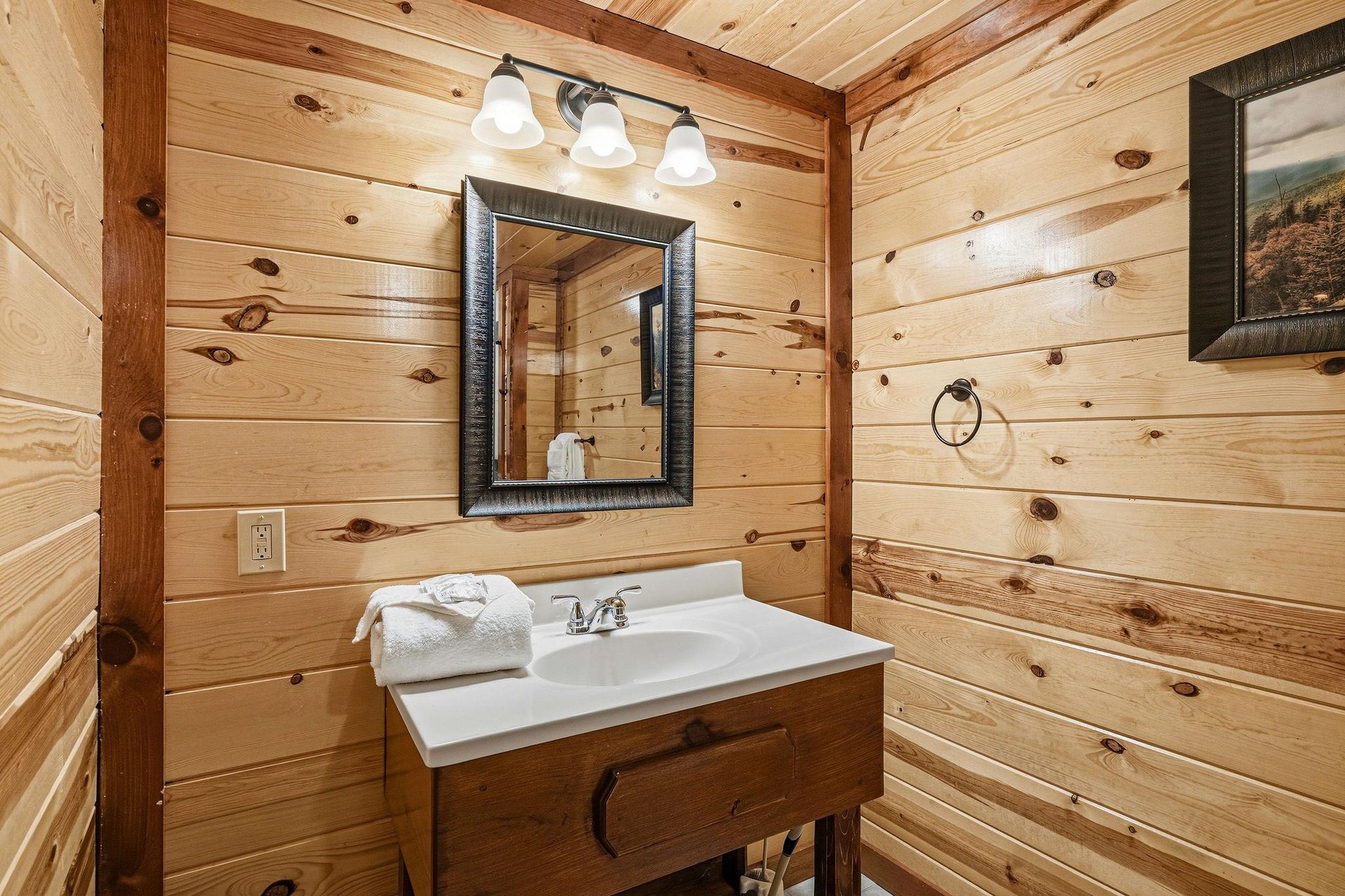 Refresh in your rustic bathroom with warm wood walls, clean white vanity, and soft lighting creating a cozy cabin atmosphere.