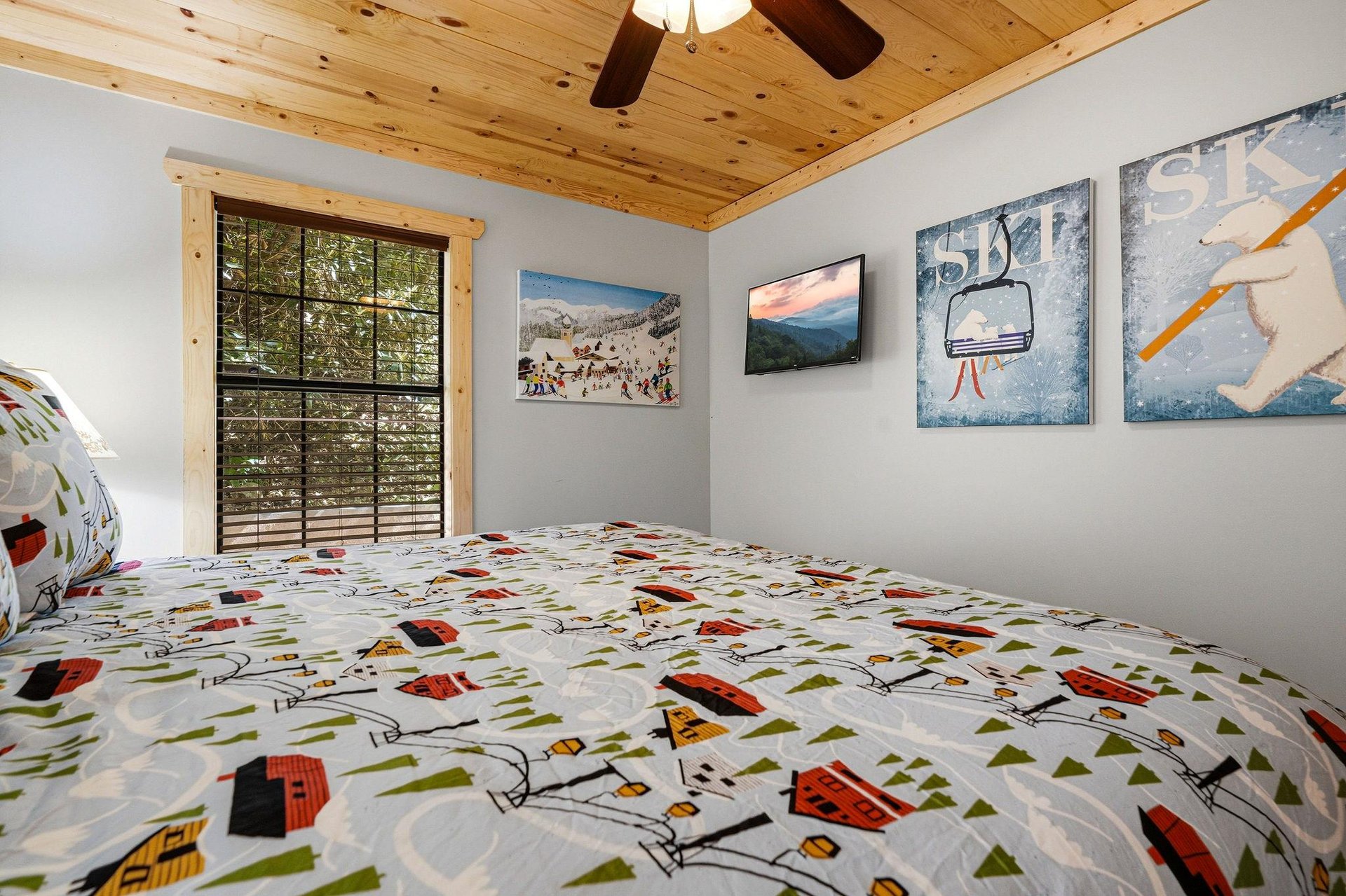 Drift off beneath warm wood ceilings in your cozy bedroom, where cheerful skithemed decor and forest views set the tone for restful mountain nights.