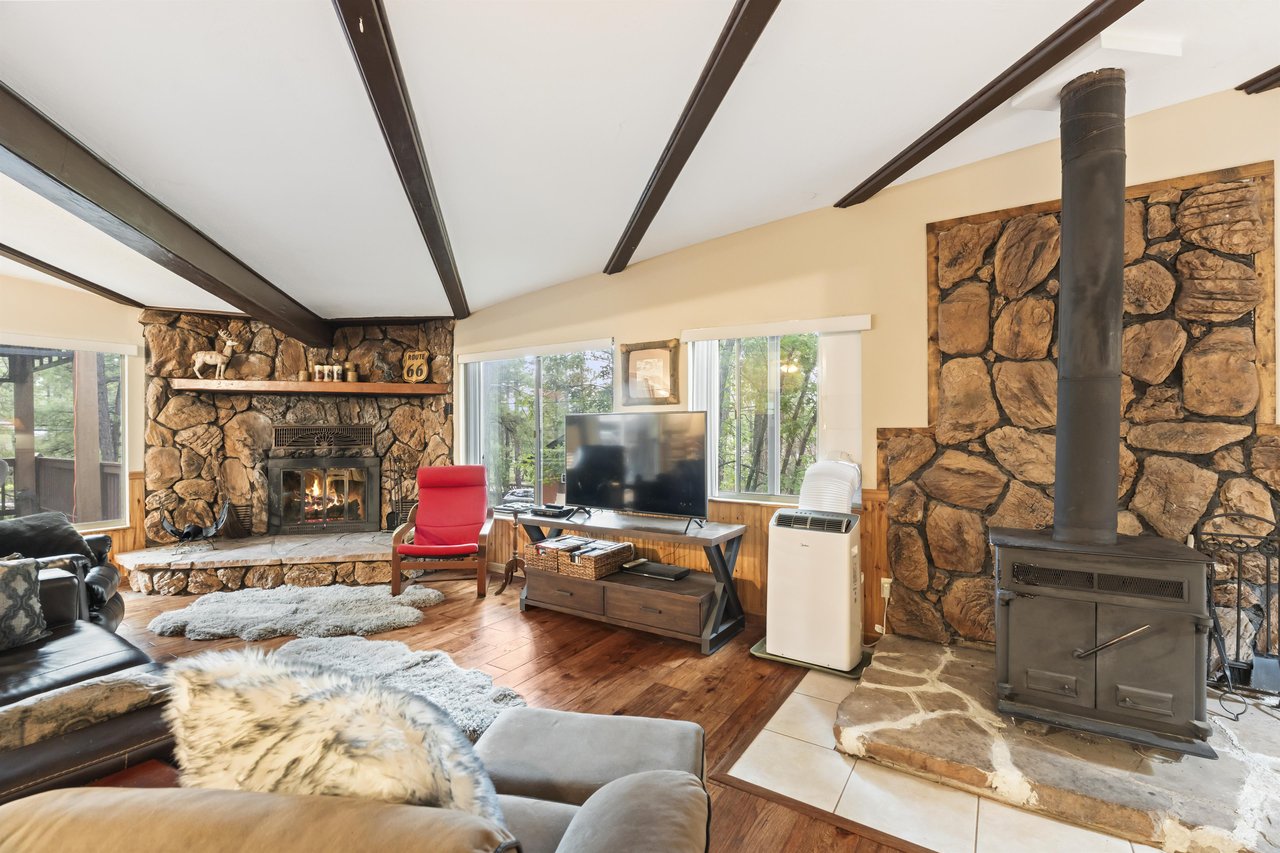 Spacious living room with a wood stove, fireplace, flatscreen TV, and ample seating.