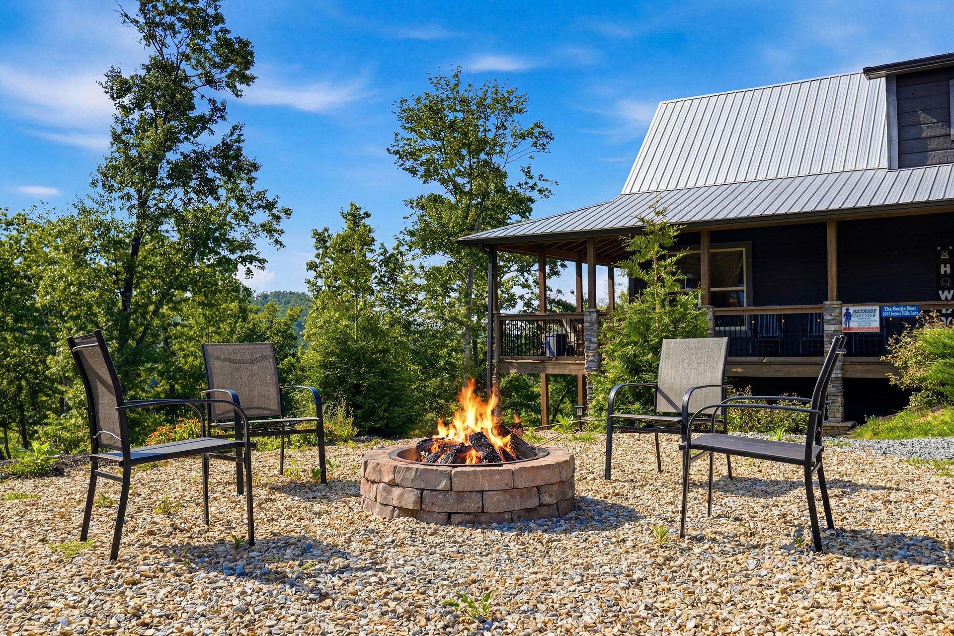 A crackling fire pit surrounded by cozy seating, perfect for evening gatherings under the open sky. Trees and rolling hillsides frame your mountain retreat.