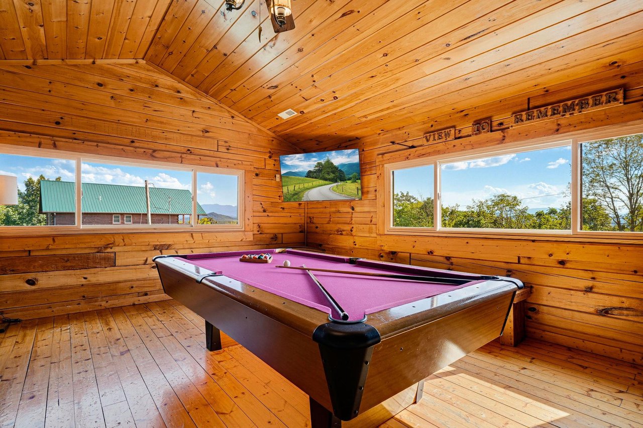 Challenge your travel companions to a friendly game of pool while soaking in stunning mountain views through expansive windows that fill this warm, woodpaneled game room with natural light.