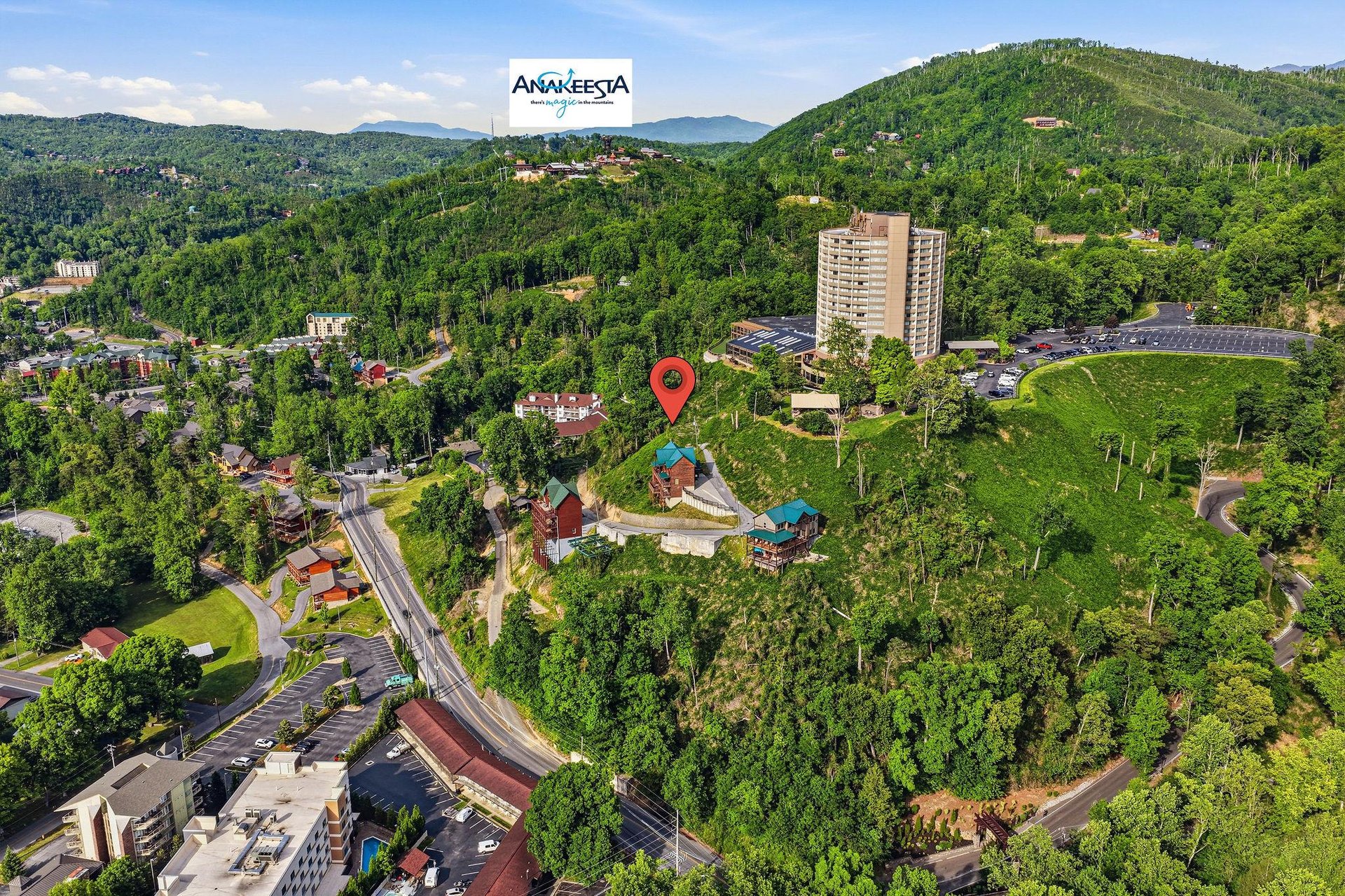 Aerial view of Anakeesta nestled among lush forested mountains, showcasing the propertys scenic mountain setting and surrounding area during a clear day.