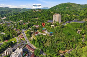 Aerial view of Anakeesta nestled among lush forested mountains, showcasing the propertys scenic mountain setting and surrounding area during a clear day.