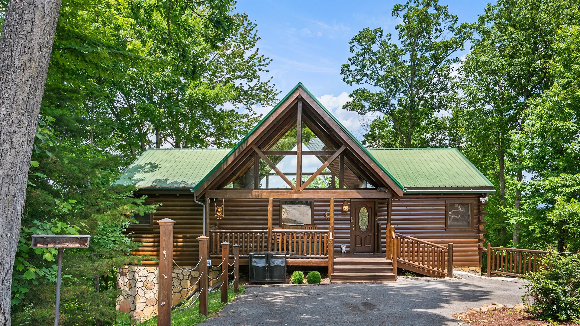 A beautiful log cabin retreat nestled among towering trees, featuring a charming green metal roof and welcoming covered porch perfect for mountain getaways.