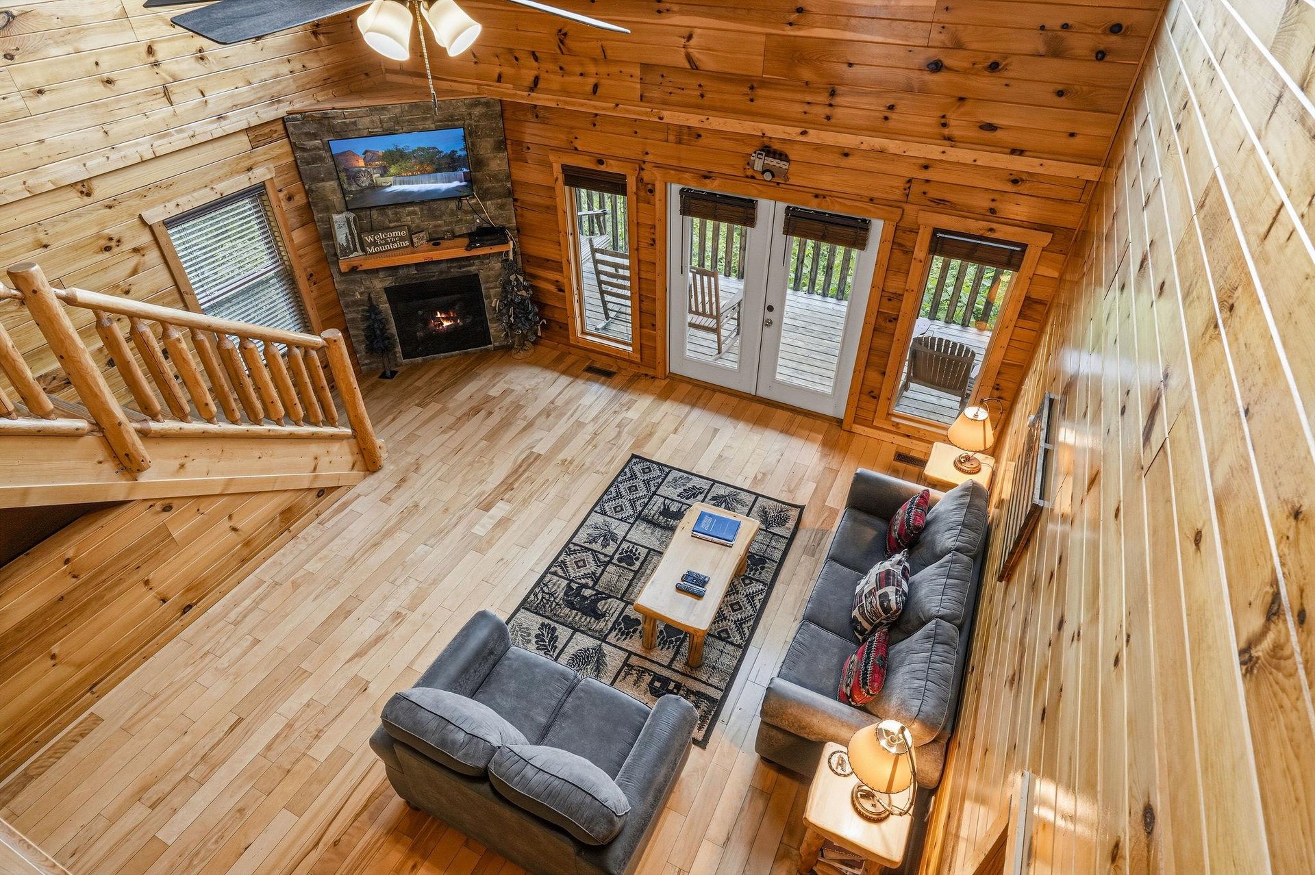Unwind in your spacious living room where warm wood surrounds you, a crackling fireplace invites cozy evenings, and sunlit doors open to your private deck nestled among the trees.
