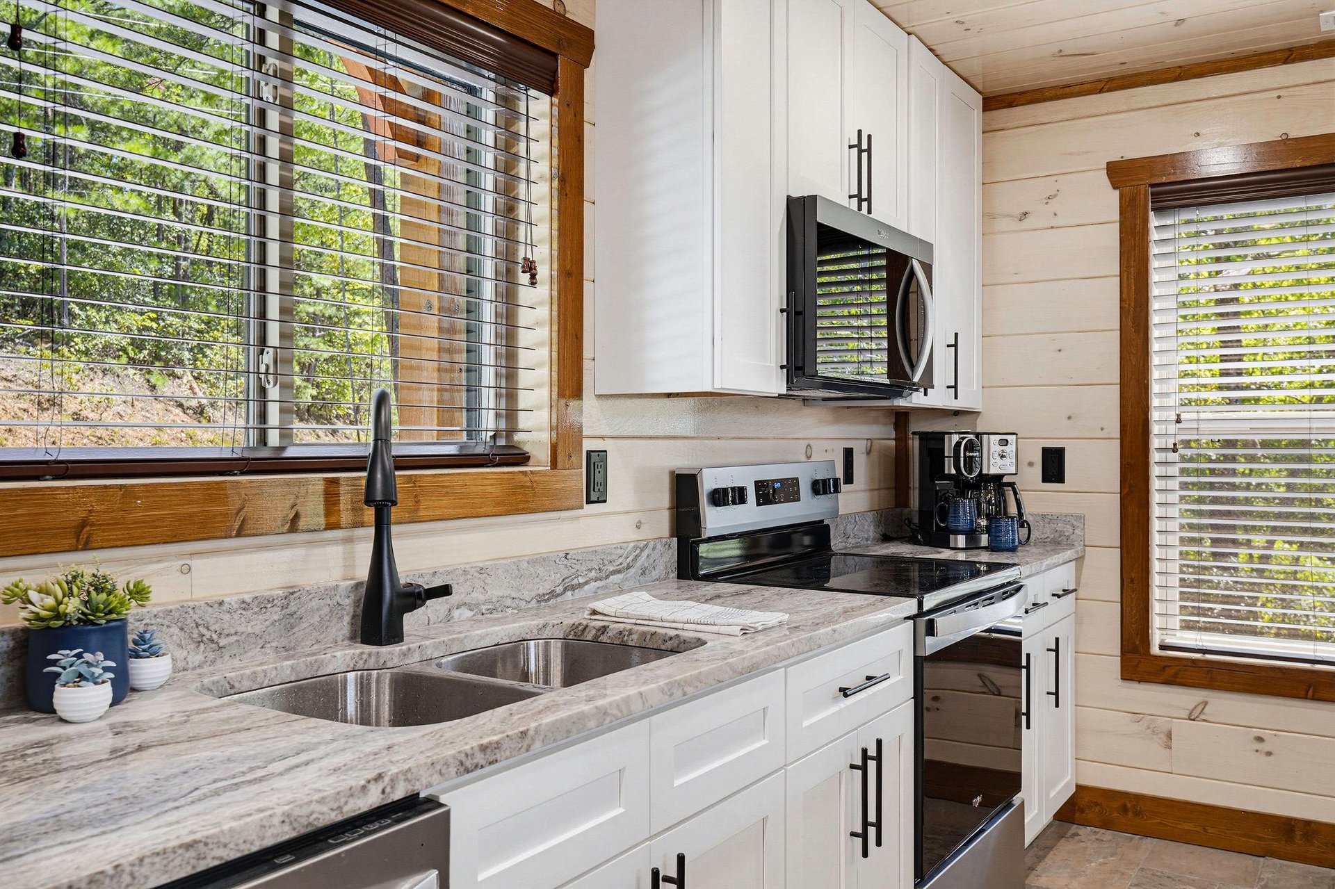 Prepare your favorite meals in this bright, fully equipped kitchen with modern appliances, granite countertops, and plenty of natural light streaming through woodenframed windows overlooking the surr