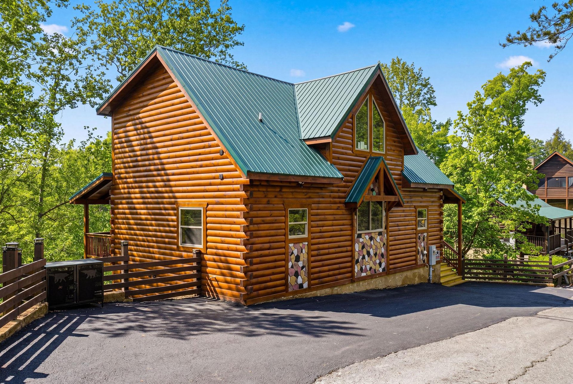 Beautiful log cabin nestled among towering trees with spacious parking and charming rustic details.