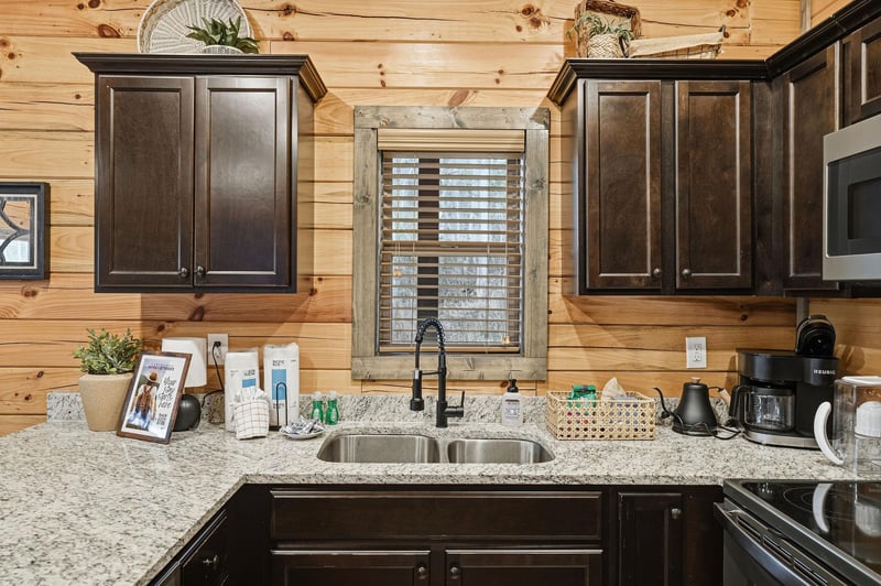 Your fully equipped kitchen features granite counters, dark wood cabinets, and modern appliances for preparing memorable meals together.