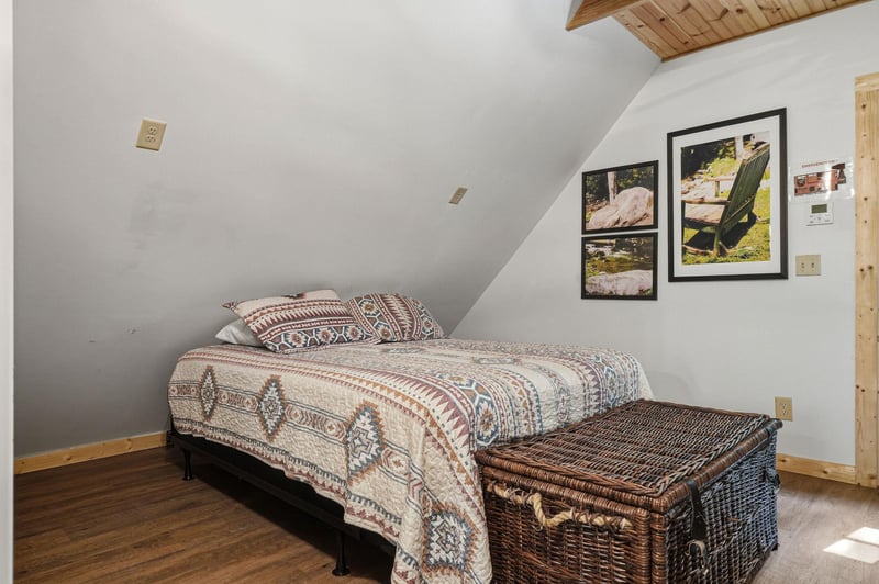 Unwind in your cozy loft bedroom with its vaulted wood ceiling, plush bedding, and charming framed art inviting restful mountain dreams.