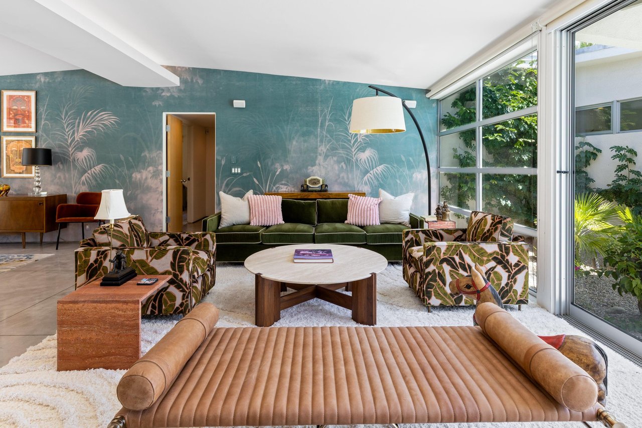 Beautiful living room that looks out to the pool and spa. Featuring a fireplace, sliding doors, and openconcept living.