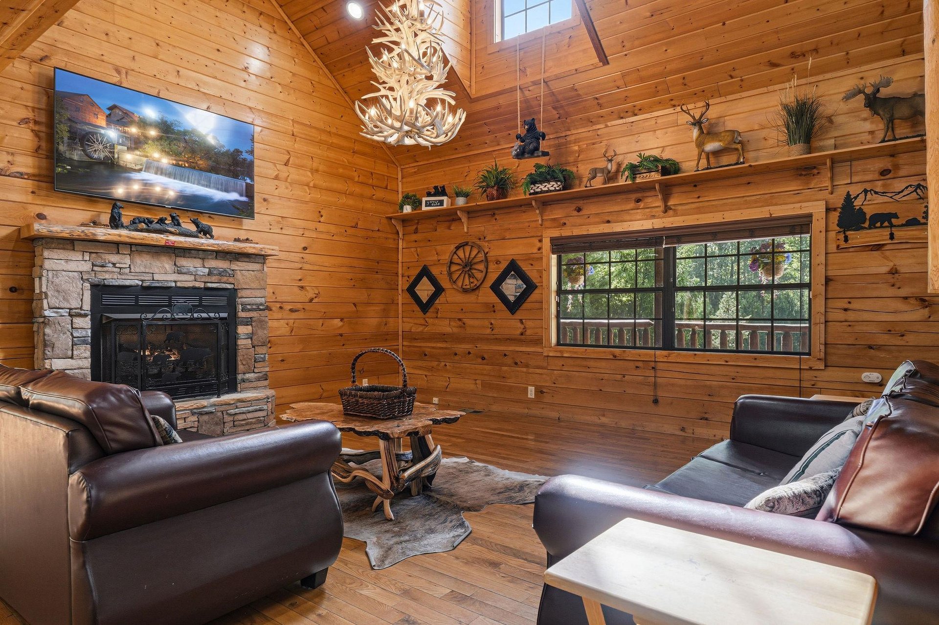 Unwind in your cozy cabin living room where rustic charm meets modern comfort. Leather seating surrounds the stone fireplace beneath vaulted wood ceilings.