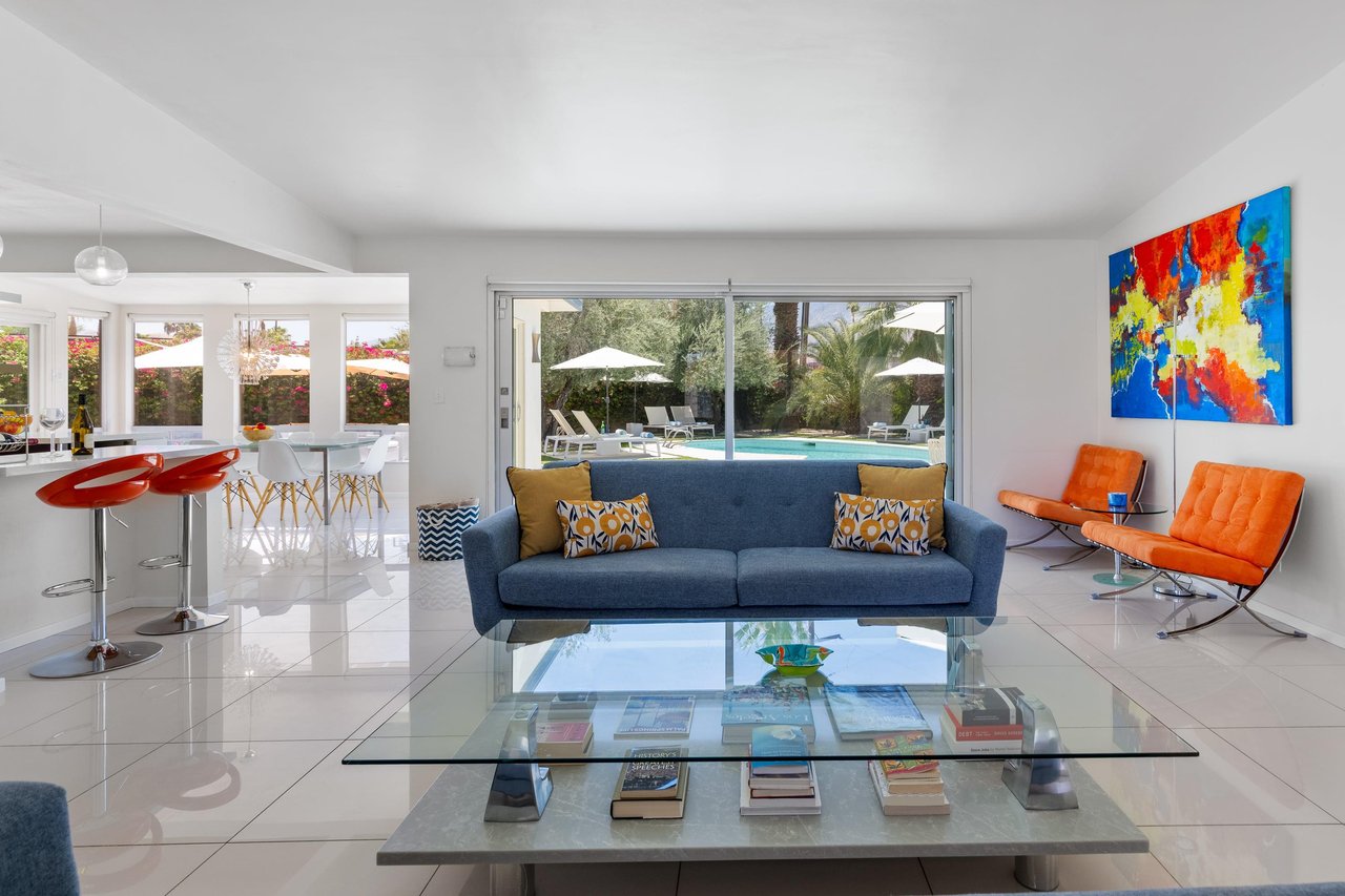 Living room with couch seating, fireplace, pool views, and openconcept living space.