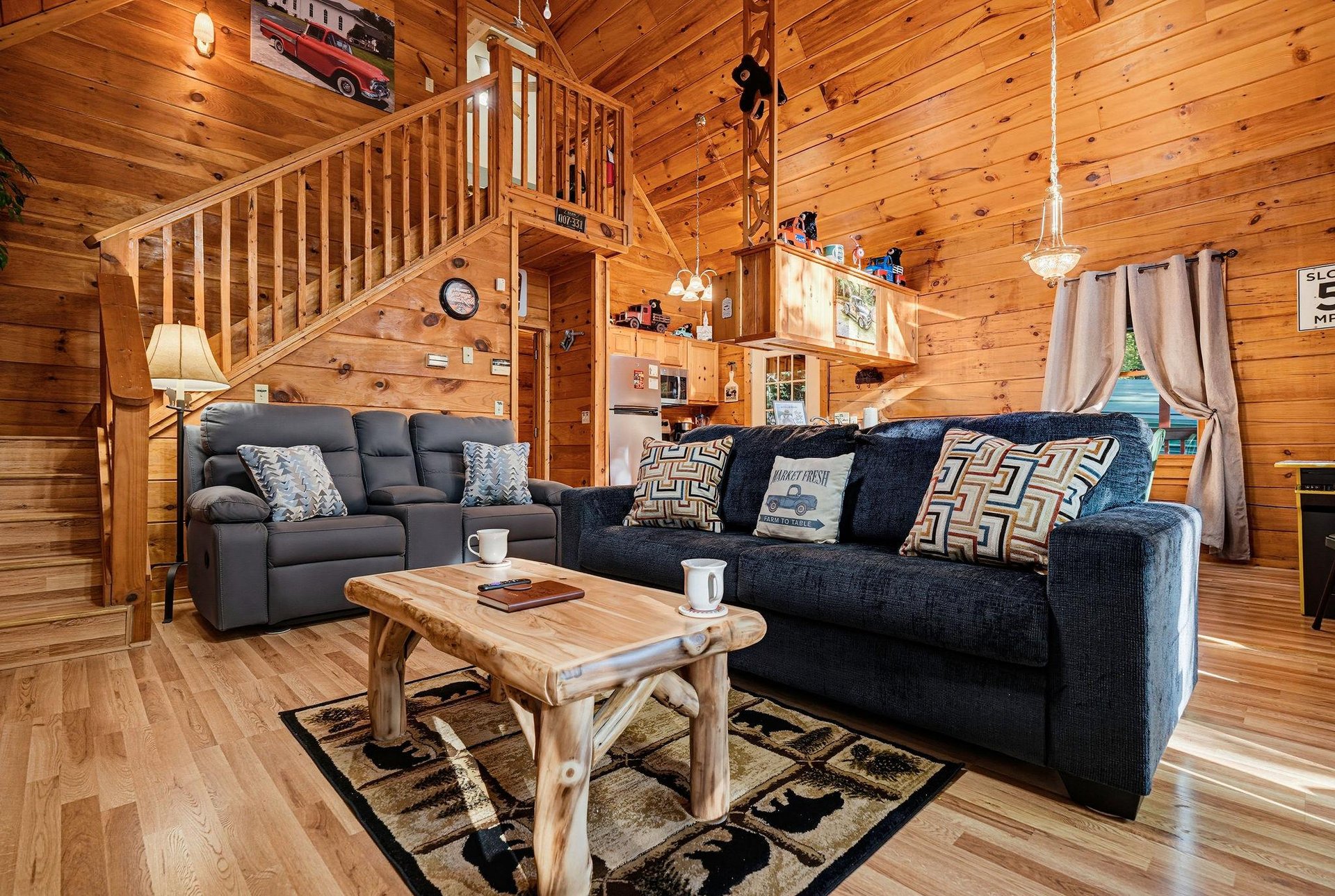 Sink into plush sofas and rustic charm in this openconcept cabin living space, where warm wood walls and a cozy loft create the perfect mountain retreat for your getaway.