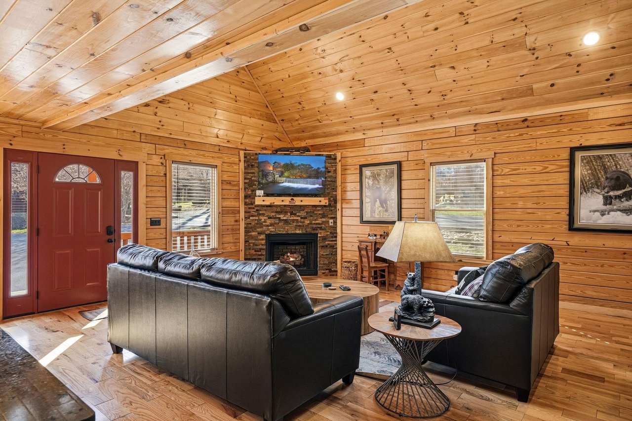 Unwind in your cozy cabin living room with rich wood walls, leather seating, and a crackling fireplace after mountain adventures.