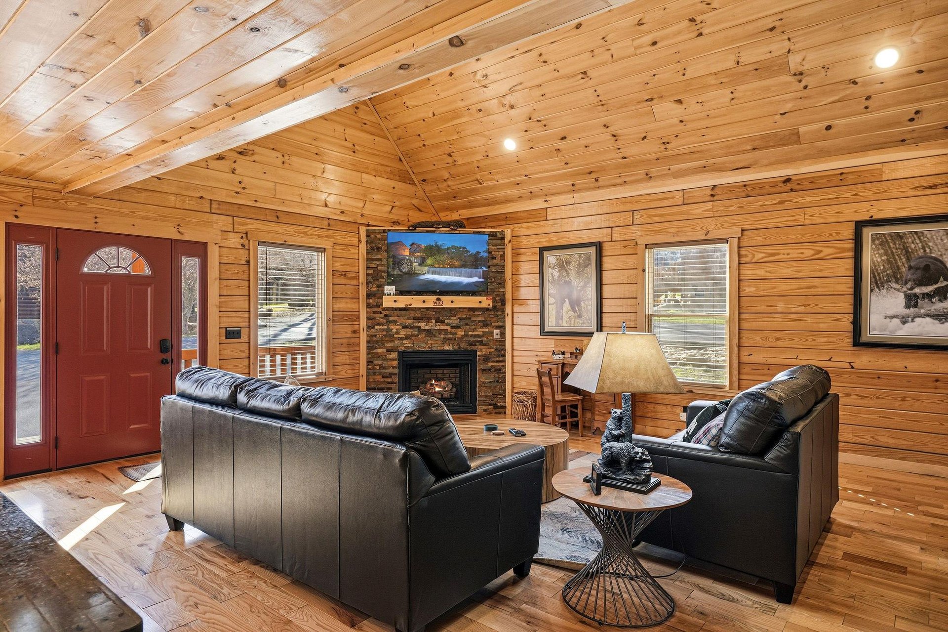Unwind in your cozy cabin living room with rich wood walls, leather seating, and a crackling fireplace after mountain adventures.