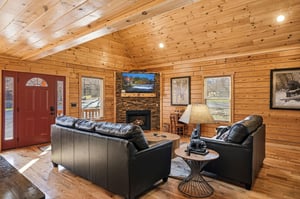 Unwind in your cozy cabin living room with rich wood walls, leather seating, and a crackling fireplace after mountain adventures.