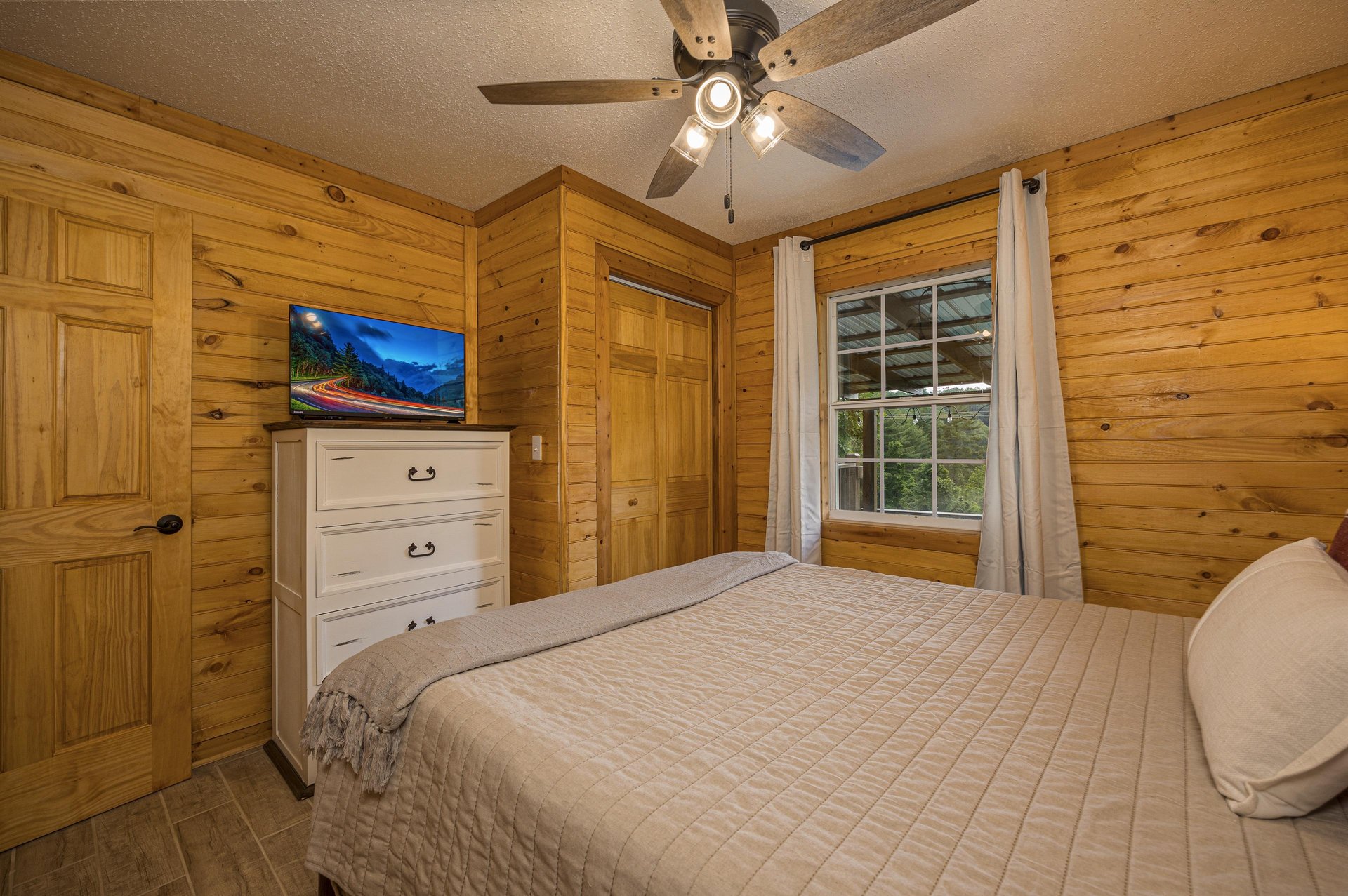 Queen bed facing dresser and tv