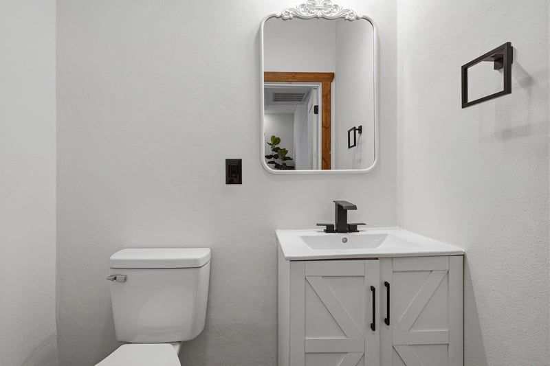 Step into your stylish bathroom featuring a charming farmhouse vanity, elegant mirror, and modern fixtures for your comfort.