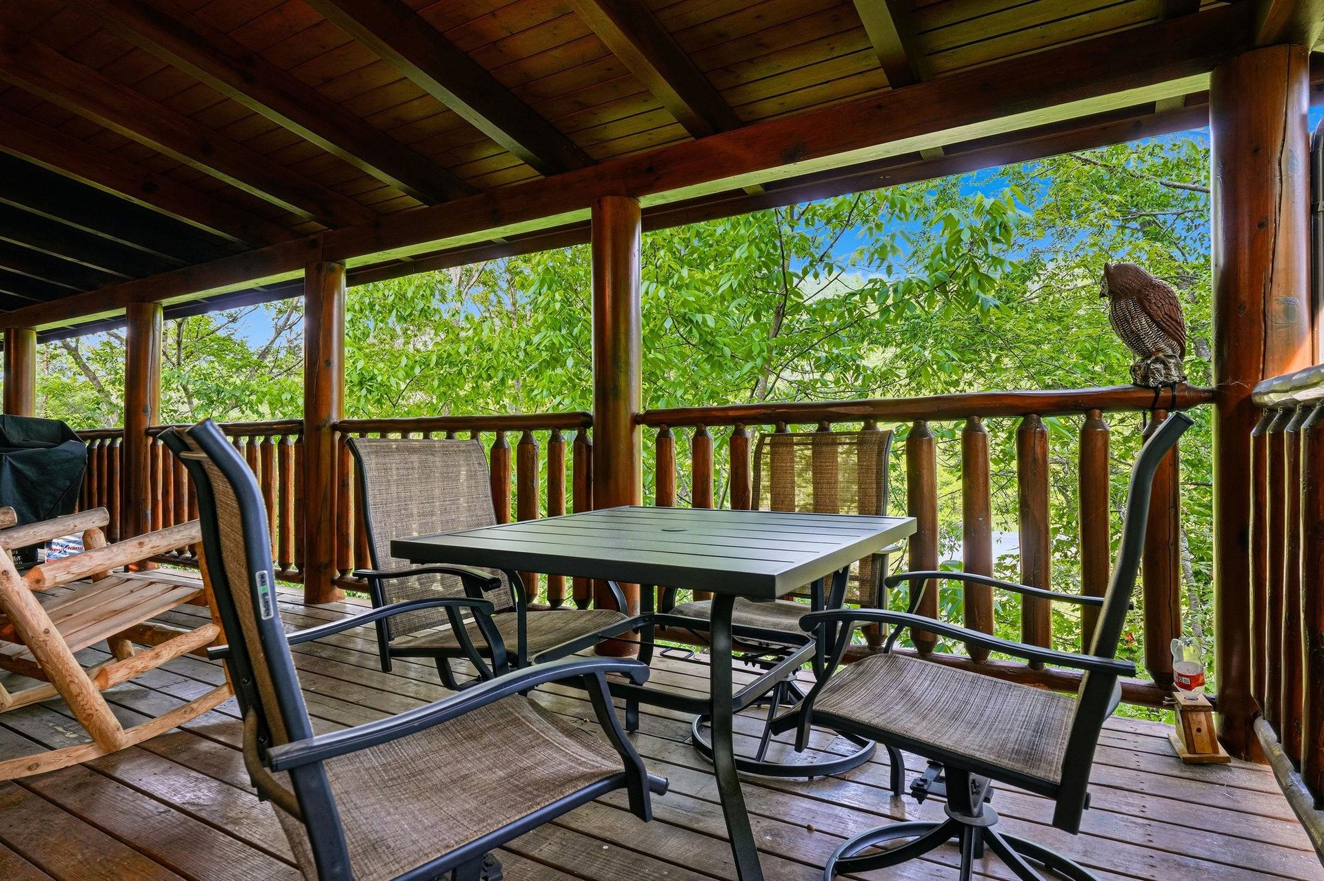 Your private covered deck offers peaceful treetop views with comfortable seating for morning coffee and outdoor dining surrounded by nature.