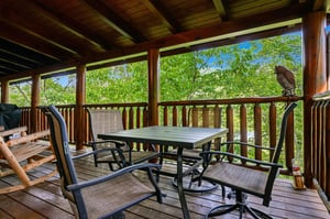 Your private covered deck offers peaceful treetop views with comfortable seating for morning coffee and outdoor dining surrounded by nature.