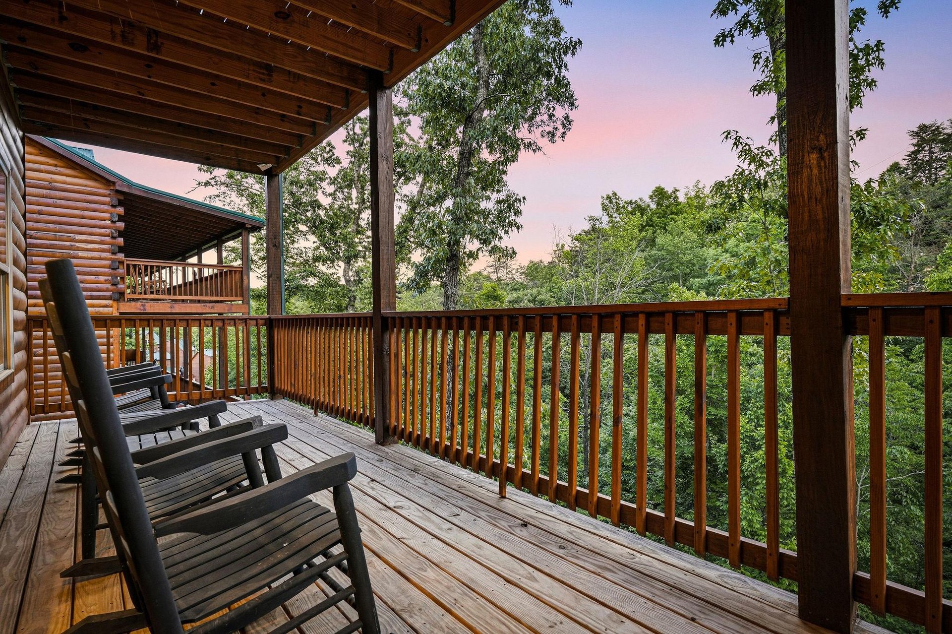A peaceful covered deck framed by forest greenery offers a serene spot to unwind with mountain breezes and soft pastel skies at dusk.