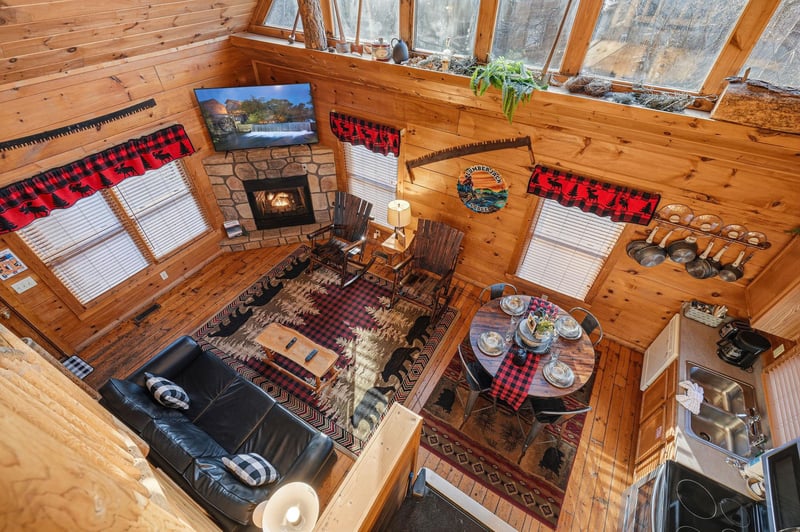 Gather around your cozy stone fireplace in this rustic log cabin living space, where plaid touches and wood beams create perfect mountain retreat vibes.